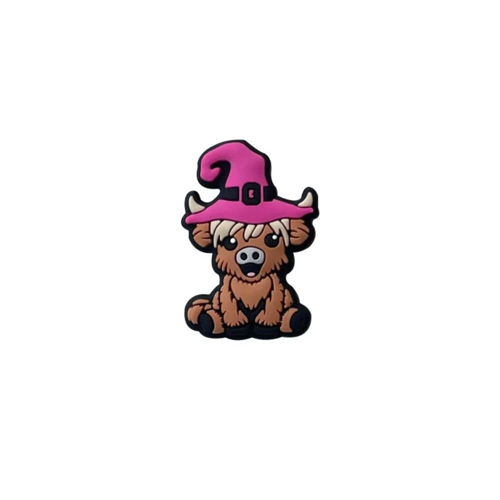 Four 3D silicone focal beads shaped like cartoon highland cows wearing witch hats in pink, yellow-green, purple, and dark purple, displayed on a white tray with a beadable pen. - Pink