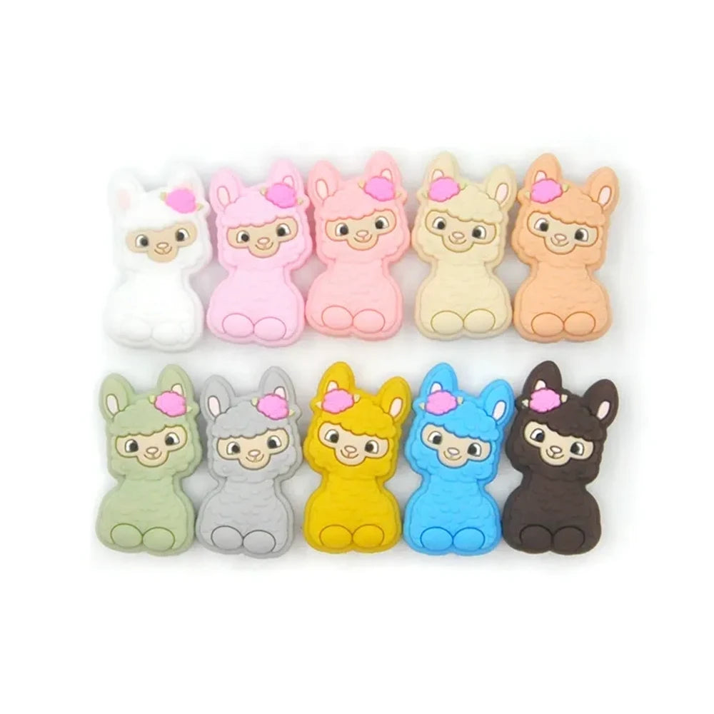 Ten colorful silicone llama alpaca focal beads in white, pink, light pink, cream, peach, green, gray, yellow, blue, and dark brown, displayed in two rows on a white background.