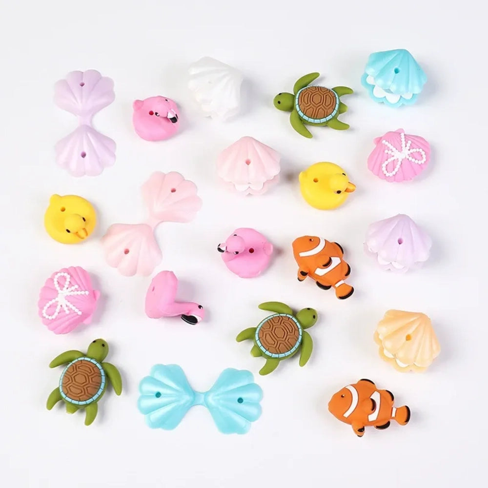 Assorted ocean animal silicone focal beads including sea turtles, clownfish, flamingos, rubber ducks, and seashells in pastel and bright colors for DIY jewelry making and beadable pens.