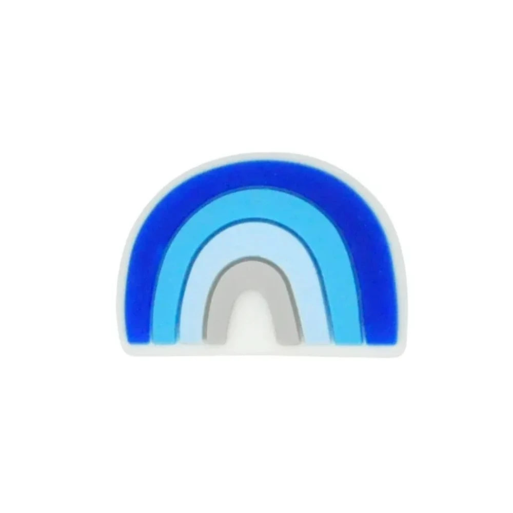 Five colorful silicone rainbow arch focal beads in various color combinations including blue-gray, multicolor, dark-mint, boho pink, and pink-teal, displayed on a wooden slice with pine cones on a star-patterned surface. - Blue