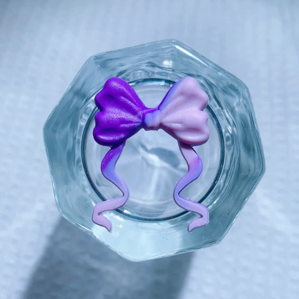 8 assorted ribbon bow silicone focal beads in purple, mint, teal swirl, hot pink, white, black glitter, turquoise, and light pink, displayed on white waffle fabric background. - 3