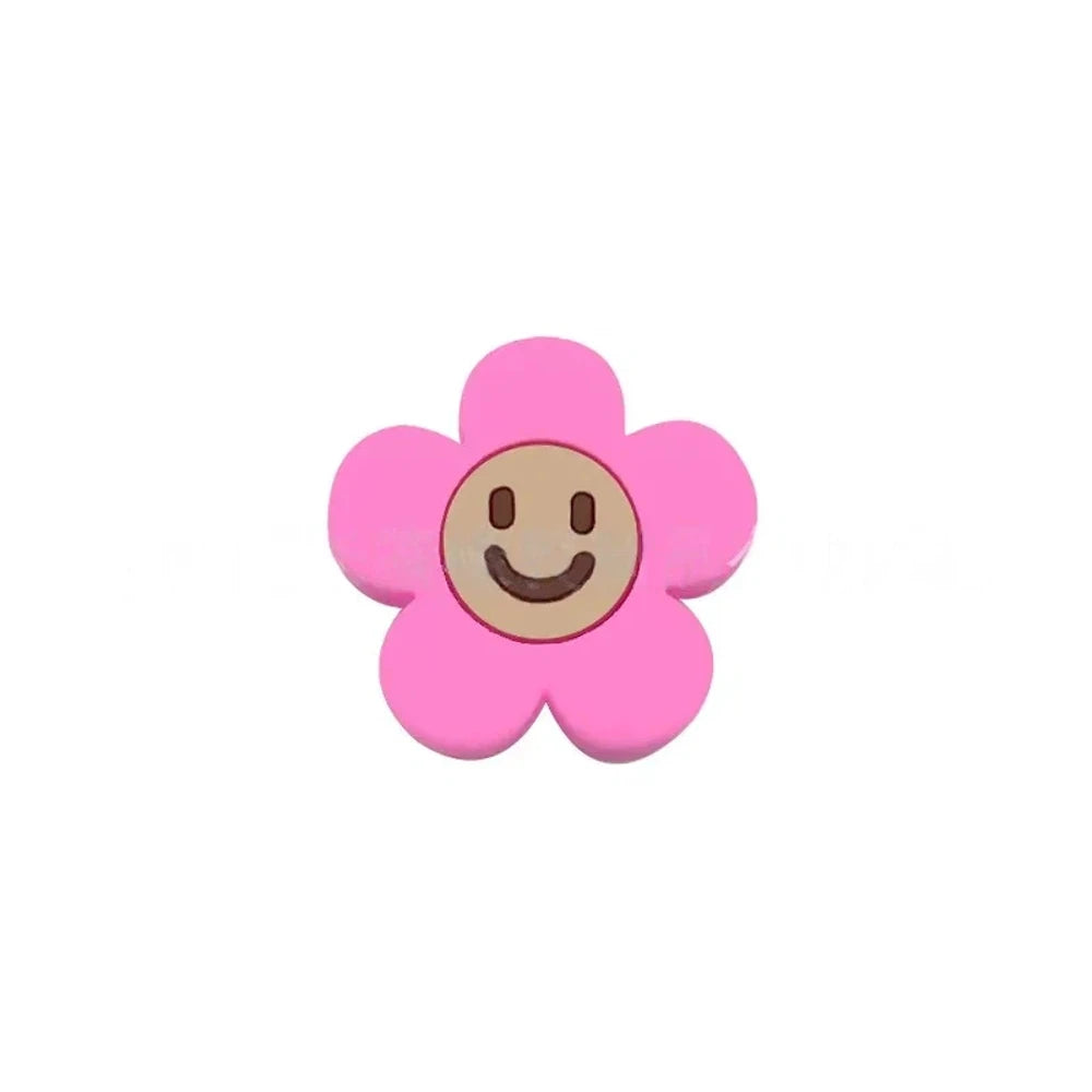 10 colorful smiley face daisy flower silicone focal beads in white, yellow, mustard, teal, sage, pink, light pink, lavender, purple, and hot pink on a tan background. - Hot Pink