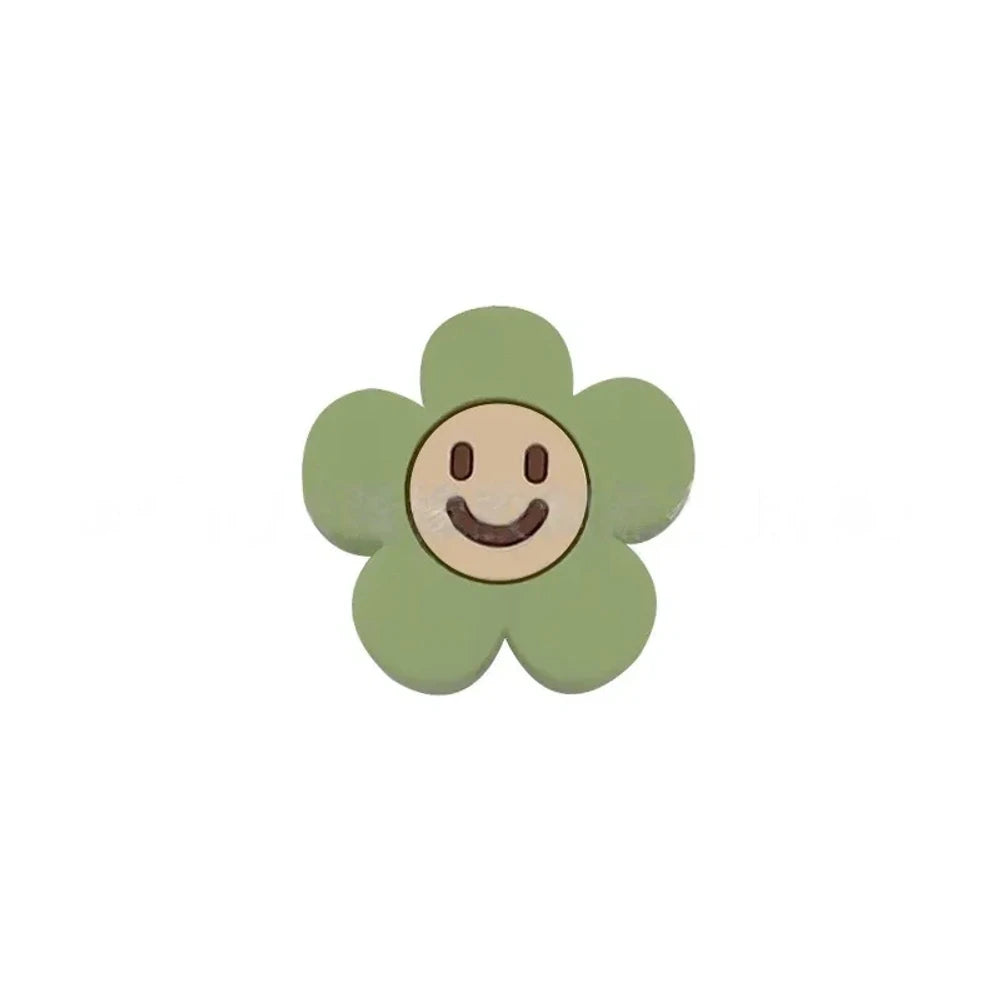 10 colorful smiley face daisy flower silicone focal beads in white, yellow, mustard, teal, sage, pink, light pink, lavender, purple, and hot pink on a tan background. - Matcha Green