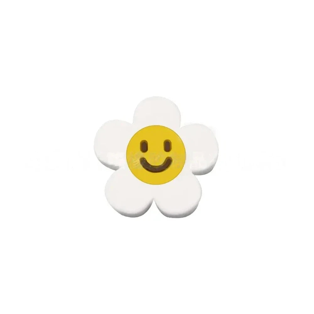 10 colorful smiley face daisy flower silicone focal beads in white, yellow, mustard, teal, sage, pink, light pink, lavender, purple, and hot pink on a tan background. - White