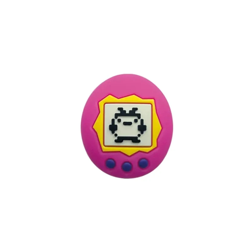 Assorted Tamagotchi silicone focal beads in pink and blue colorways displayed alongside four completed beadable pens on a pink background, showing pixel pet virtual pet screen design detail. - Pink