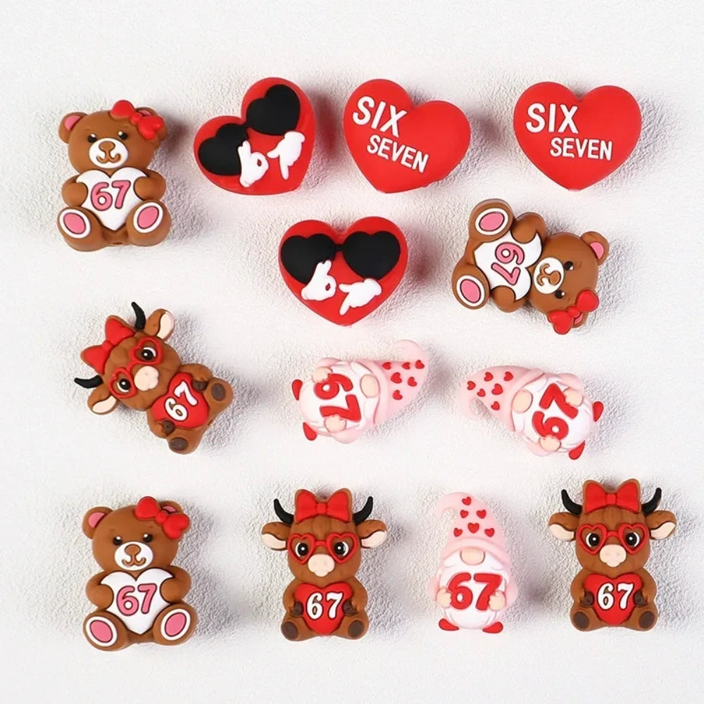 Assorted Valentine's Day silicone focal beads featuring teddy bears holding 67 hearts, highland cows with red bows, heart-shaped sunglasses, gnomes, and SIX SEVEN heart beads in red and pink tones