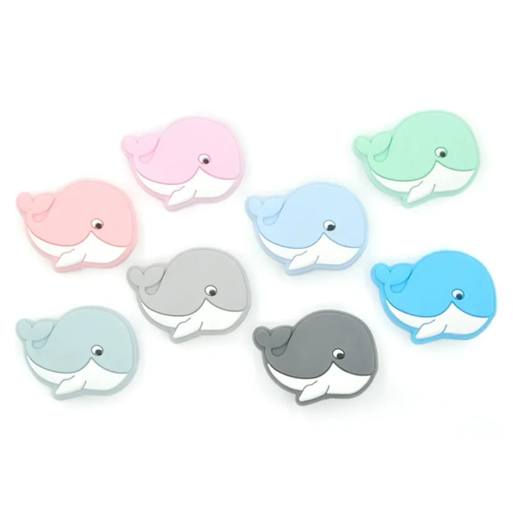 Eight cute whale silicone focal beads in assorted pastel and bold colors including pink, mint, blue, gray, and teal on a white background.