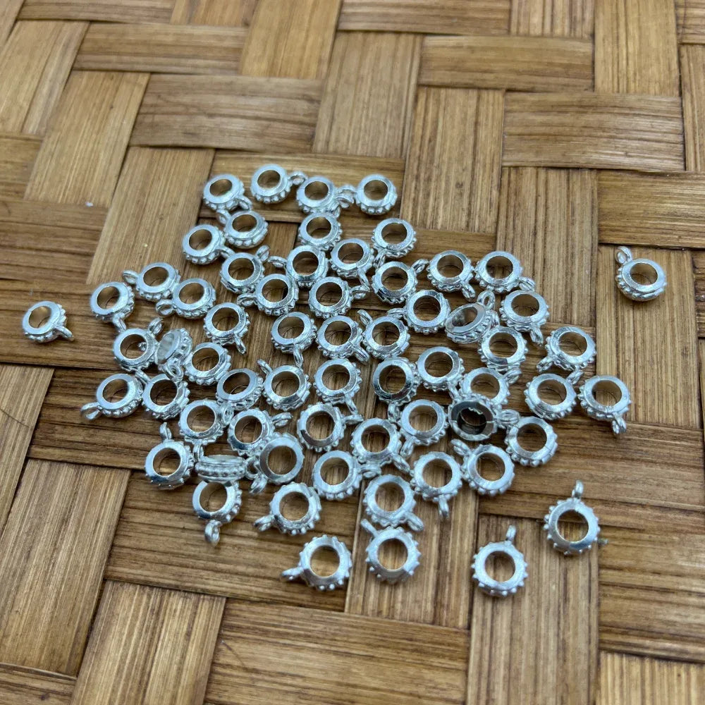 Silver metal dotted ring bail beads with side charm loop scattered on woven bamboo surface, used for beadable pens, keychains, badge reels, and DIY jewelry making.