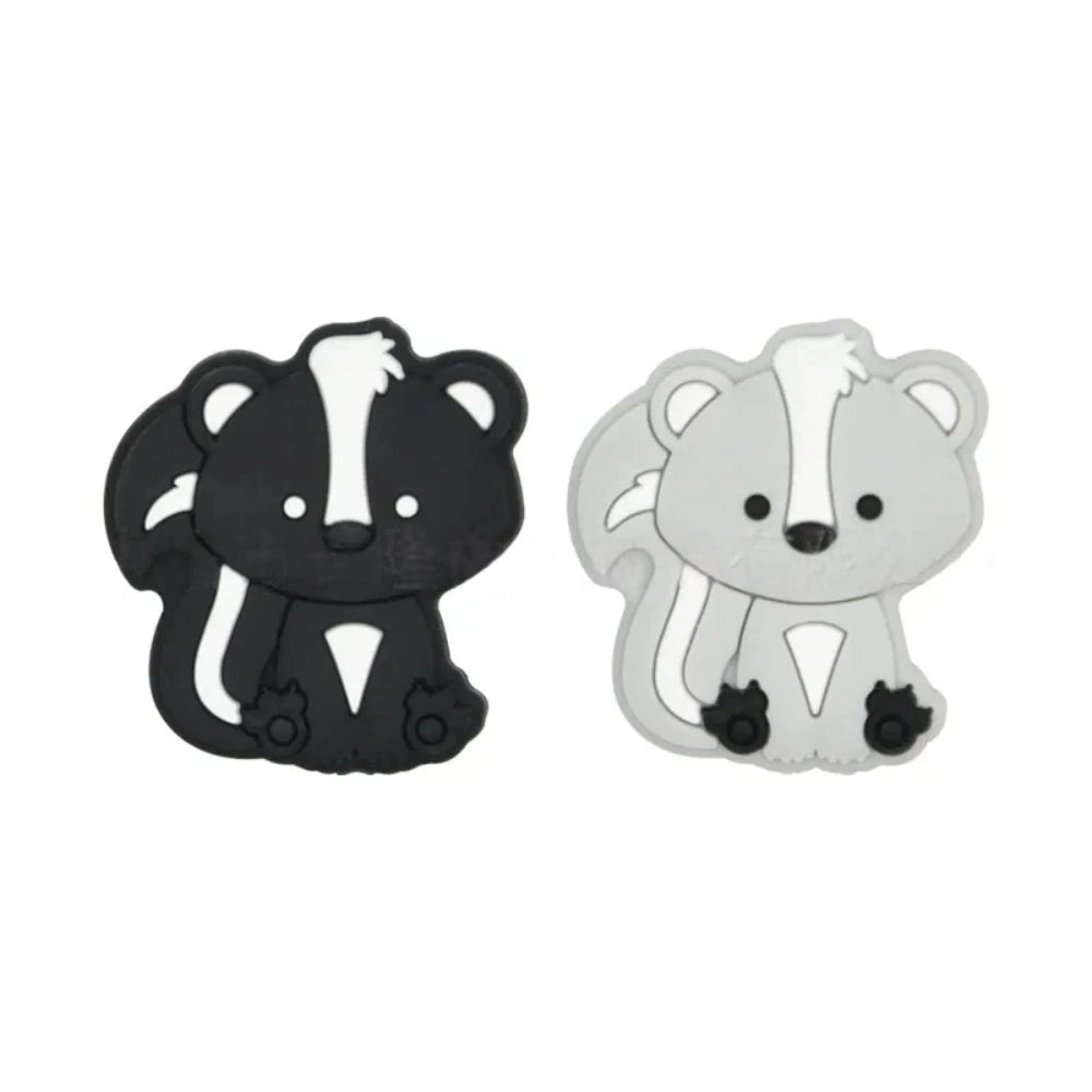 Two cute cartoon skunk silicone focal beads side by side — one black with white stripes and one gray with white stripes — for beadable pens and DIY crafts.