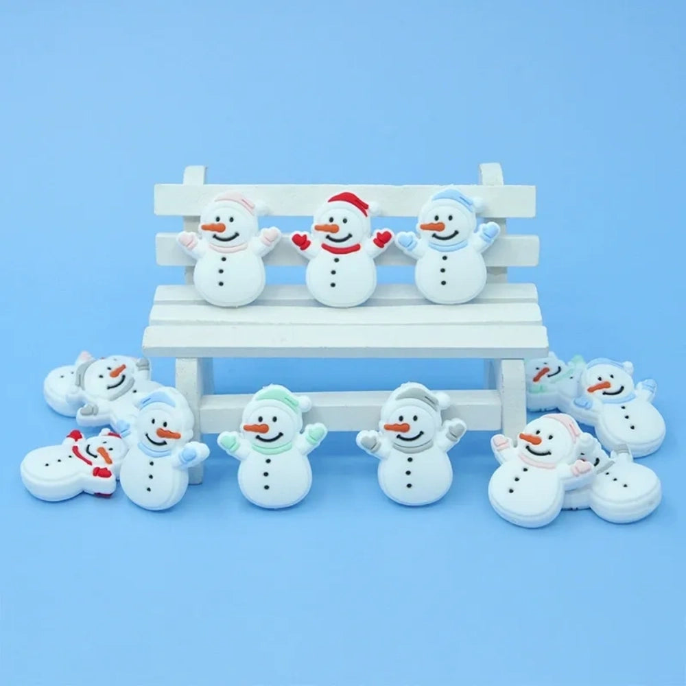 Assorted color snowman silicone focal beads with hats and scarves displayed on a miniature white bench, shown in red, blue, green, and pink accent variations on a light blue background. - Random Mixed
