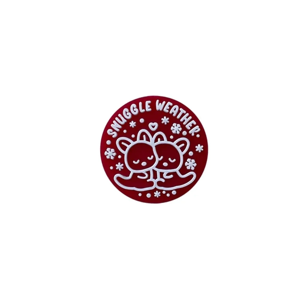 Snuggle Weather Bear silicone focal beads in pink, red, navy blue, dark red, and teal colors displayed on a white ceramic plate and pink surface, featuring a cute cartoon bear hugging design with snowflakes and 'Snuggle Weather' text. - 1