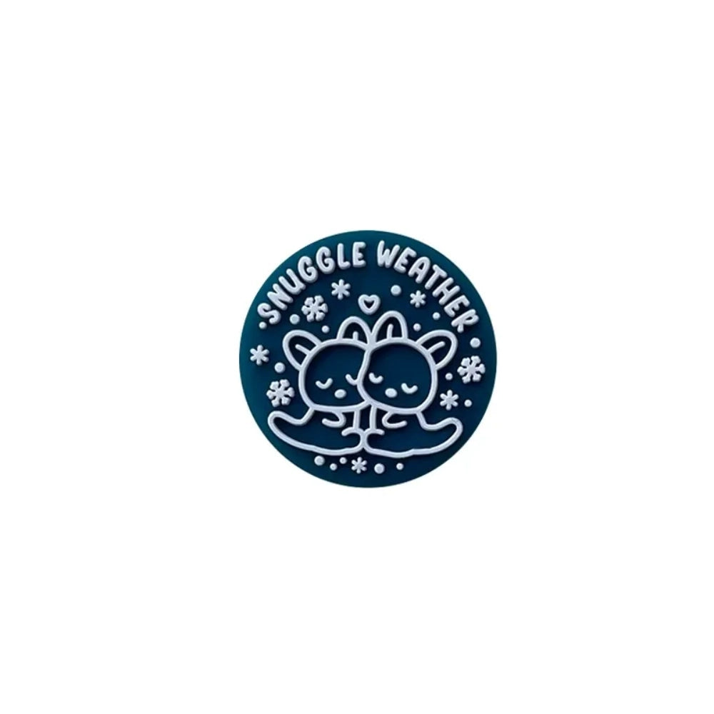 Snuggle Weather Bear silicone focal beads in pink, red, navy blue, dark red, and teal colors displayed on a white ceramic plate and pink surface, featuring a cute cartoon bear hugging design with snowflakes and 'Snuggle Weather' text. - 6