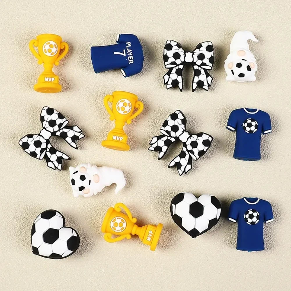 Set of 12 soccer-themed 3D silicone focal beads including MVP trophy, player jersey, football bow, gnome, heart football, and blue shirt designs for DIY crafts.