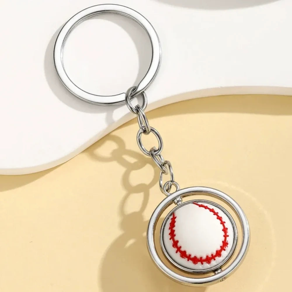 Set of 5 spinning sports ball keychain charms including soccer ball, basketball, football, baseball, and golf ball with silver metal rings on a cream background - Baseball
