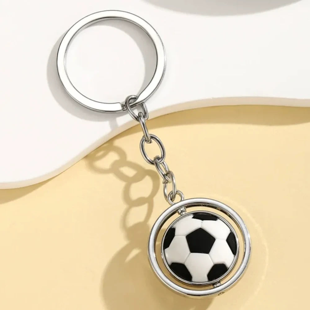 Set of 5 spinning sports ball keychain charms including soccer ball, basketball, football, baseball, and golf ball with silver metal rings on a cream background - Football