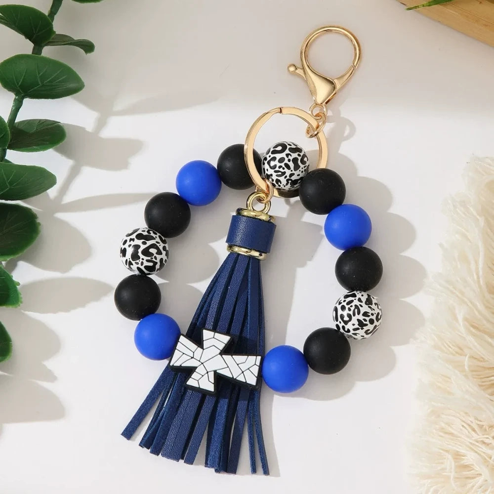 Set of 6 silicone bead stretch bracelet keychains featuring sports cross charms and leather tassels in assorted colors including red, blue, green, orange, black and white with leopard print beads and gold lobster clasp hardware. - Blue