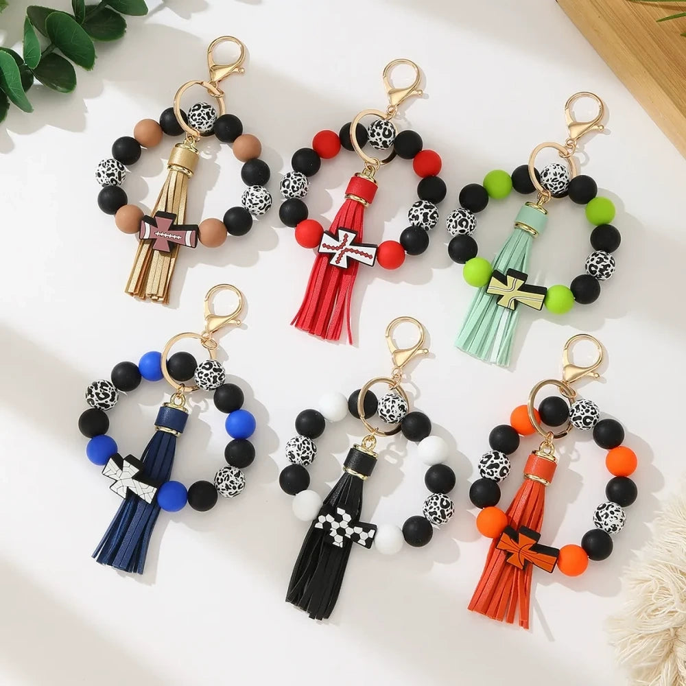 Set of 6 silicone bead stretch bracelet keychains featuring sports cross charms and leather tassels in assorted colors including red, blue, green, orange, black and white with leopard print beads and gold lobster clasp hardware. - Random Mixed