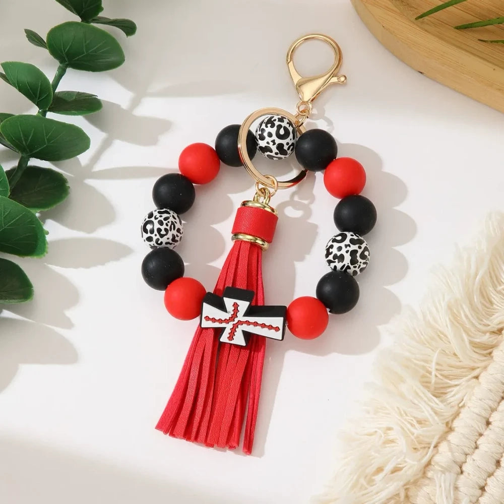 Set of 6 silicone bead stretch bracelet keychains featuring sports cross charms and leather tassels in assorted colors including red, blue, green, orange, black and white with leopard print beads and gold lobster clasp hardware. - Red