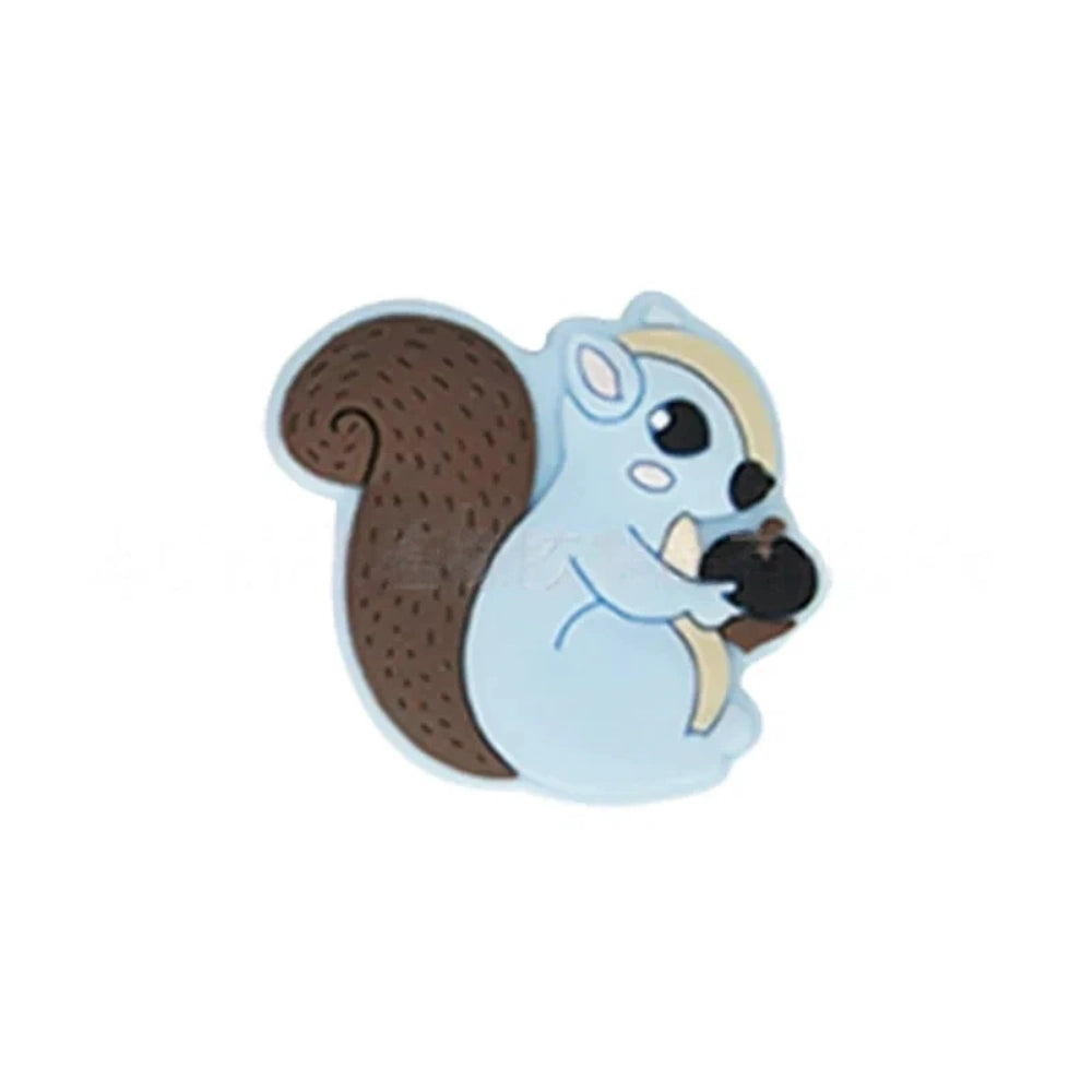Six cute cartoon squirrel silicone focal beads holding acorns in brown, yellow, grey, dark pink, light pink, and blue colors arranged on a miniature white bench. - Light Blue