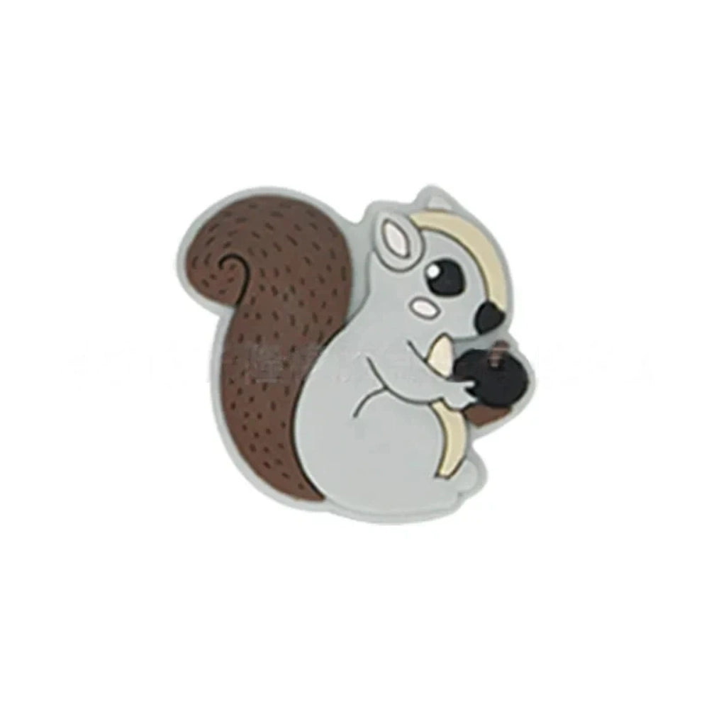 Six cute cartoon squirrel silicone focal beads holding acorns in brown, yellow, grey, dark pink, light pink, and blue colors arranged on a miniature white bench. - Light Gray