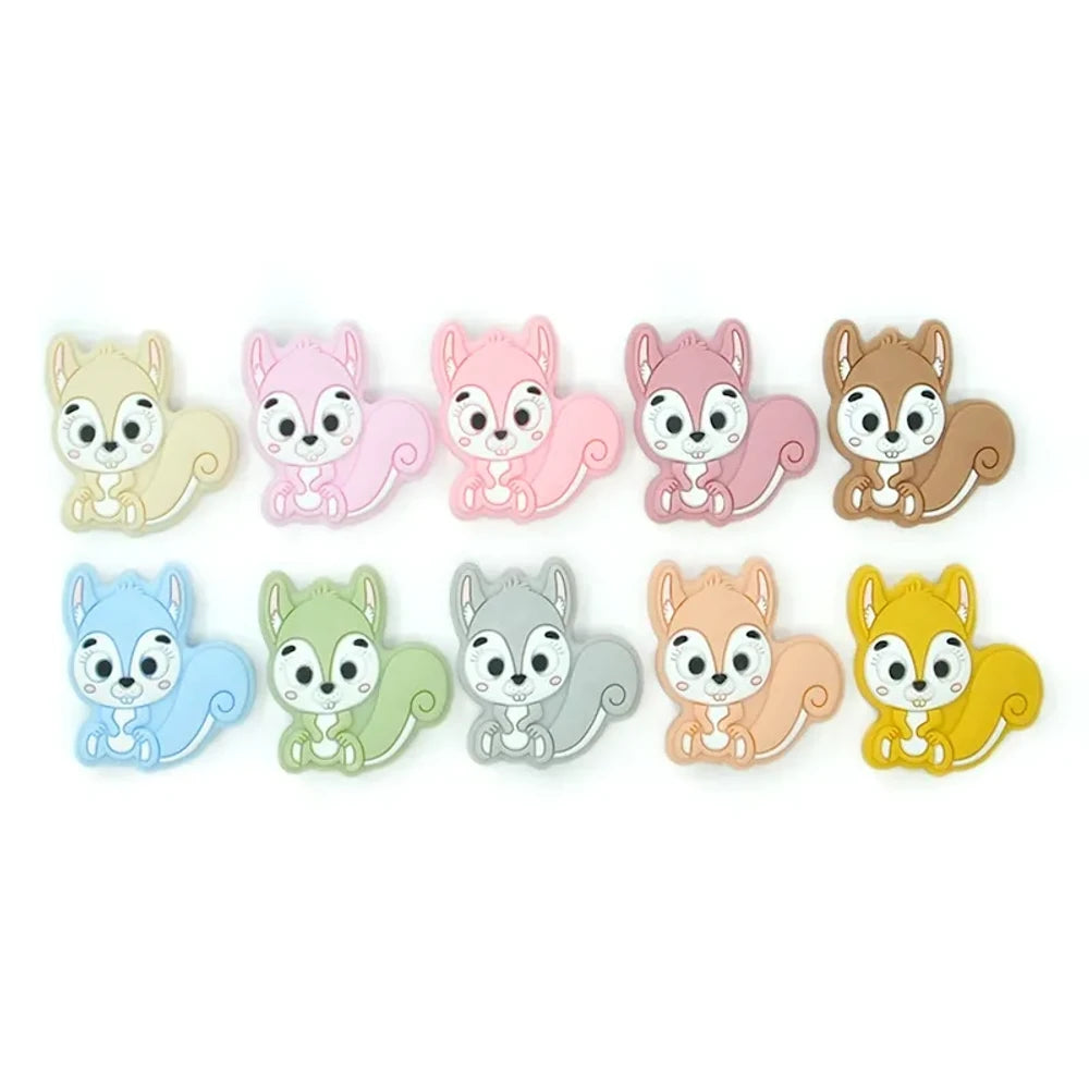 Ten colorful cartoon squirrel silicone focal beads in beige, pink, rose, mauve, brown, blue, green, gray, peach, and yellow arranged in two rows on a white background.