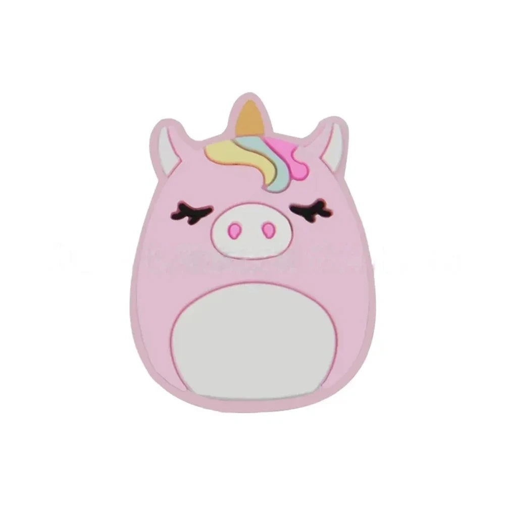 Four Squishmallow-style silicone focal beads featuring two pink unicorn pig characters and two cat characters (black and calico), displayed on a white surface with a pink background. - Light Pink