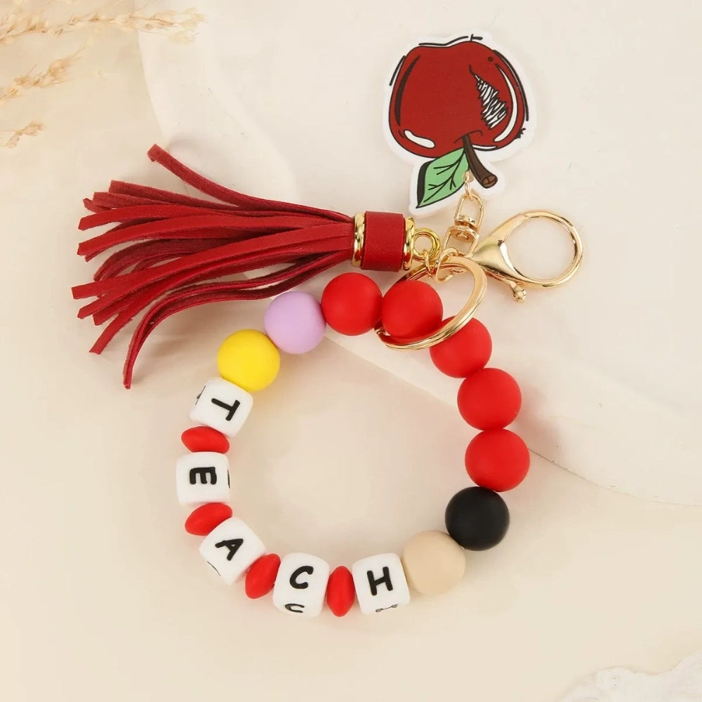 Colorful TEACH letter printed silicone beads on beaded bracelet keychains with tassels and teacher-themed charms including pencil, apple, rainbow, and Be Kind pendants. - AB