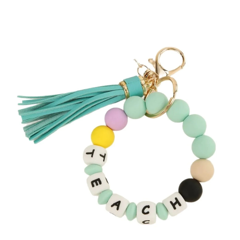 Colorful TEACH letter printed silicone beads on beaded bracelet keychains with tassels and teacher-themed charms including pencil, apple, rainbow, and Be Kind pendants. - D