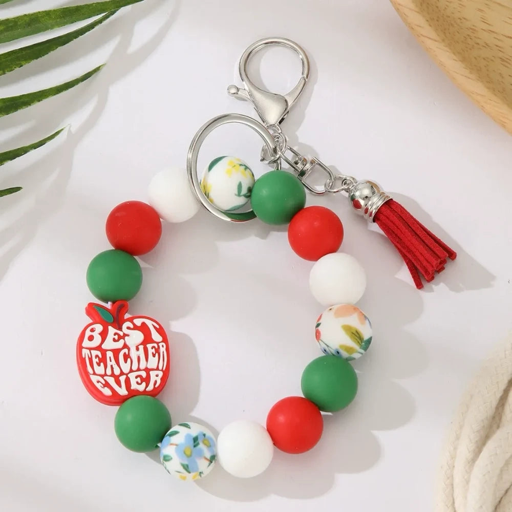 Eight teacher-themed silicone bead keychains featuring apple and pencil charms, colorful red, green, yellow, and mint beads with tassels, labeled Best Teacher Ever and A+ Teacher. - 2