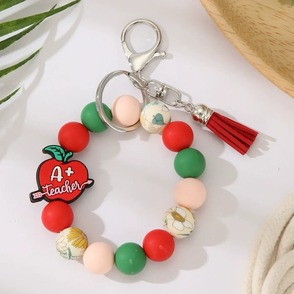 Eight teacher-themed silicone bead keychains featuring apple and pencil charms, colorful red, green, yellow, and mint beads with tassels, labeled Best Teacher Ever and A+ Teacher. - 3