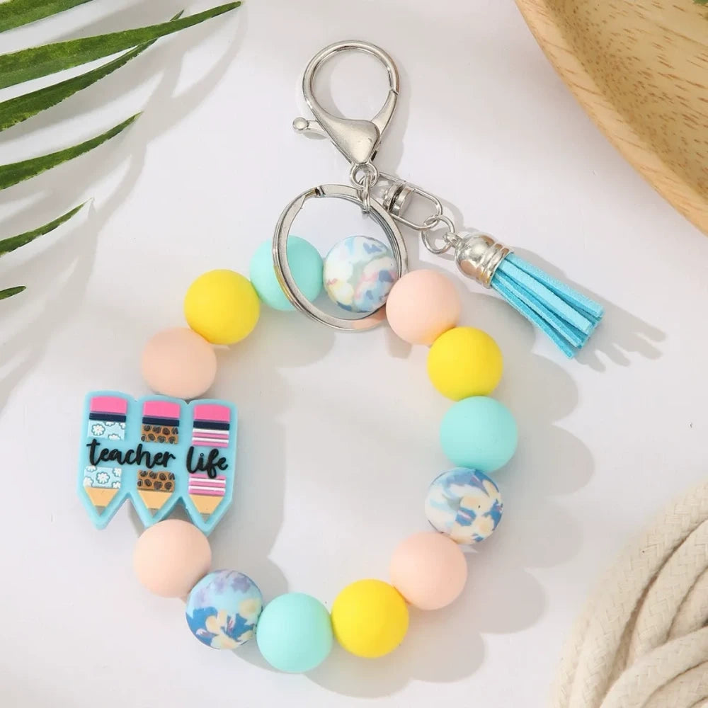 Eight teacher-themed silicone bead keychains featuring apple and pencil charms, colorful red, green, yellow, and mint beads with tassels, labeled Best Teacher Ever and A+ Teacher. - 4