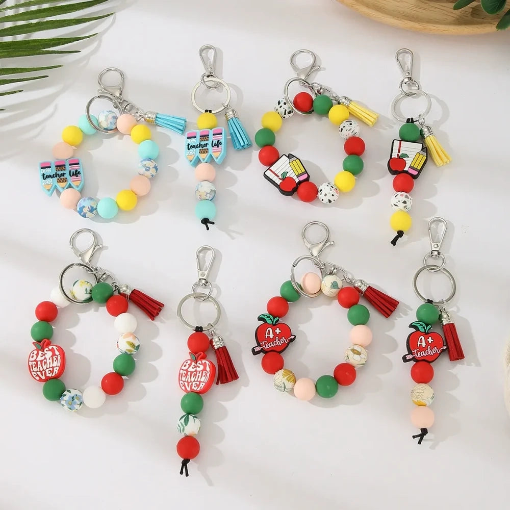 Eight teacher-themed silicone bead keychains featuring apple and pencil charms, colorful red, green, yellow, and mint beads with tassels, labeled Best Teacher Ever and A+ Teacher. - Random Mixed