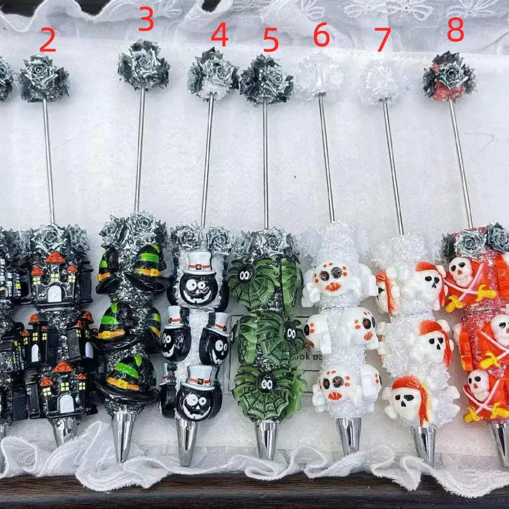 Numbered selection of Halloween themed rhinestone pens with haunted house, mummy, pumpkin, spider web, ghost, skull, and skeleton character designs.