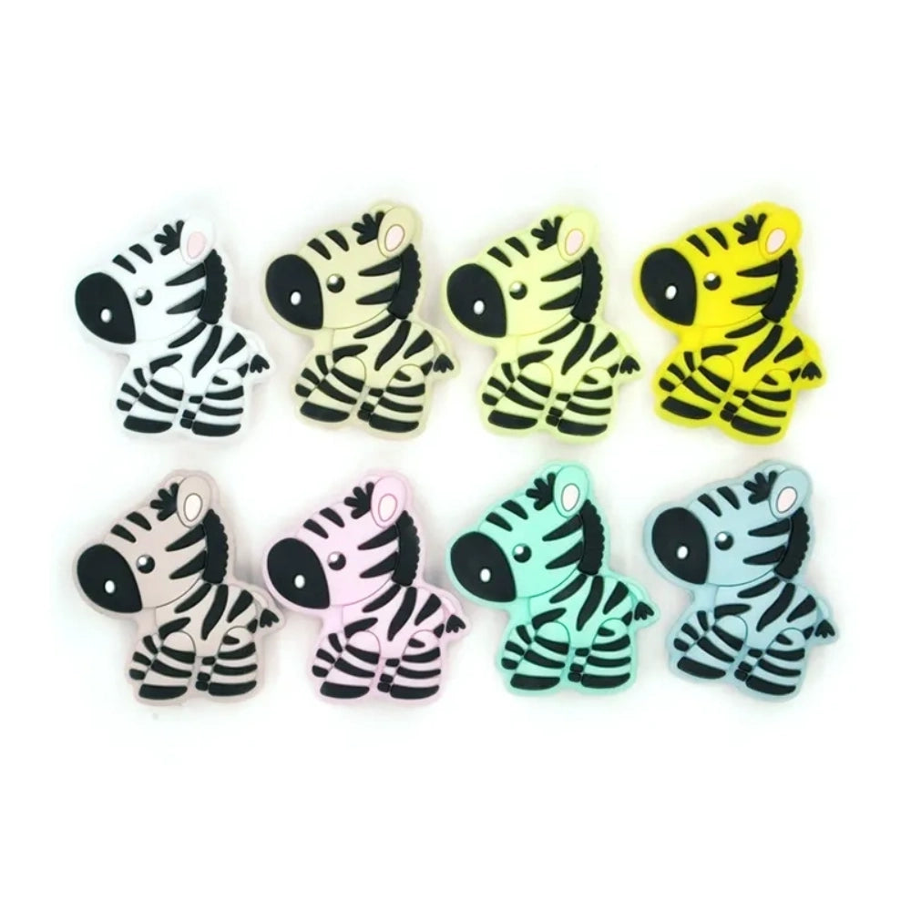 Eight cartoon zebra silicone focal beads in assorted colors including white, cream, yellow, light gray, pink, mint, and blue-gray with black stripe detailing, displayed on white background.